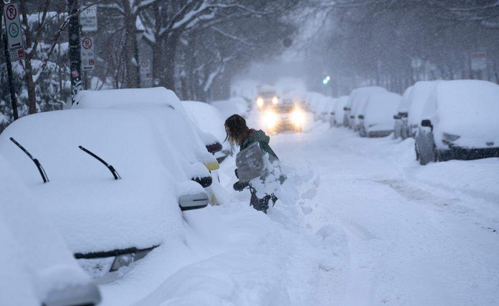 A woman digs her car out of a snowbank during a winter storm in Montreal on Wednesday, Feb. 13, 2019.