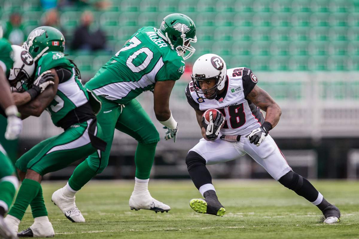 REGINA, SK - JUNE 14: DJ Harper #28 of the Ottawa RedBlacks ducks around the tackle of Derek Walker #70 of the Saskatchewan Roughriders during pre-season week B of the 2014 CFL season in a game between the Ottawa RedBlacks and Saskatchewan Roughriders at Mosaic Stadium on June 14, 2014 in Regina, Saskatchewan, Canada.  