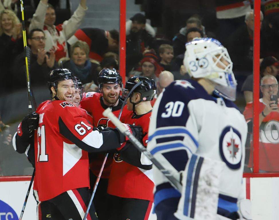 Ottawa Senators right wing Mark Stone (61) celebrates his goal with teammates Ben Harpur (67) and Mark Borowiecki (74) as Winnipeg Jets goaltender Laurent Brossoit (30) looks on during first period NHL hockey action in Ottawa on Saturday, February 9, 2019.