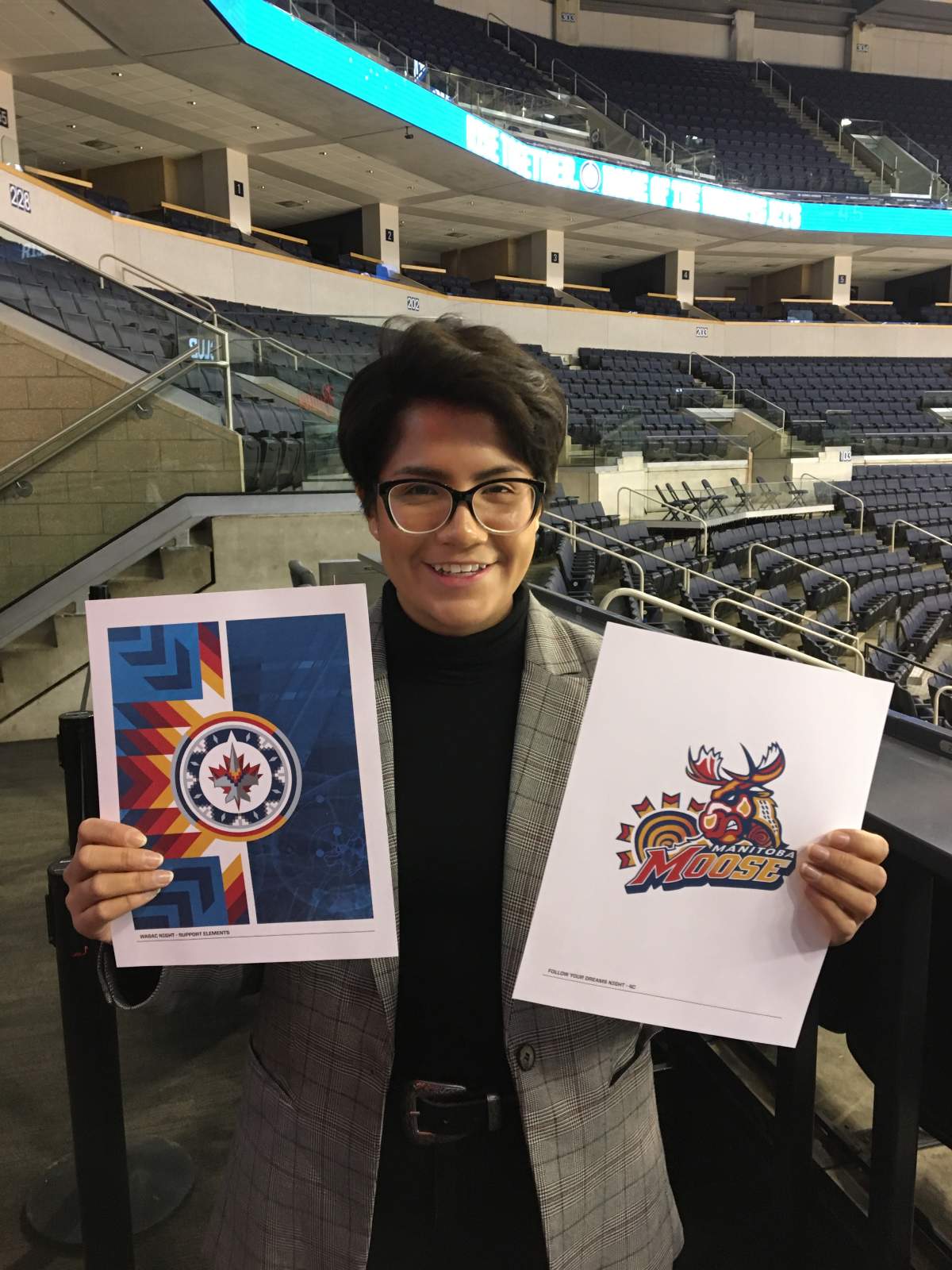 Leticia Spence, graphic design student who holding up the specialty logos she created for the Winnipeg Jets and Manitoba Moose
