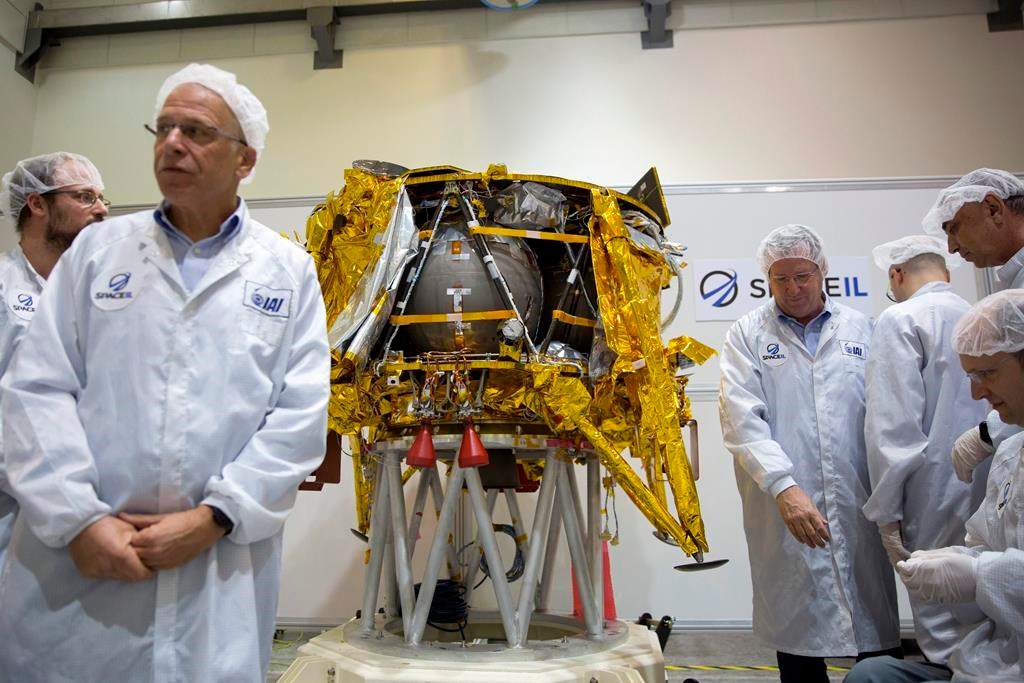 In this Monday, Dec. 17, 2018 file photo, technicians stand next to the SpaceIL lunar module, an unmanned spacecraft, on display in a special clean room during a press tour of their facility near Tel Aviv, Israel.