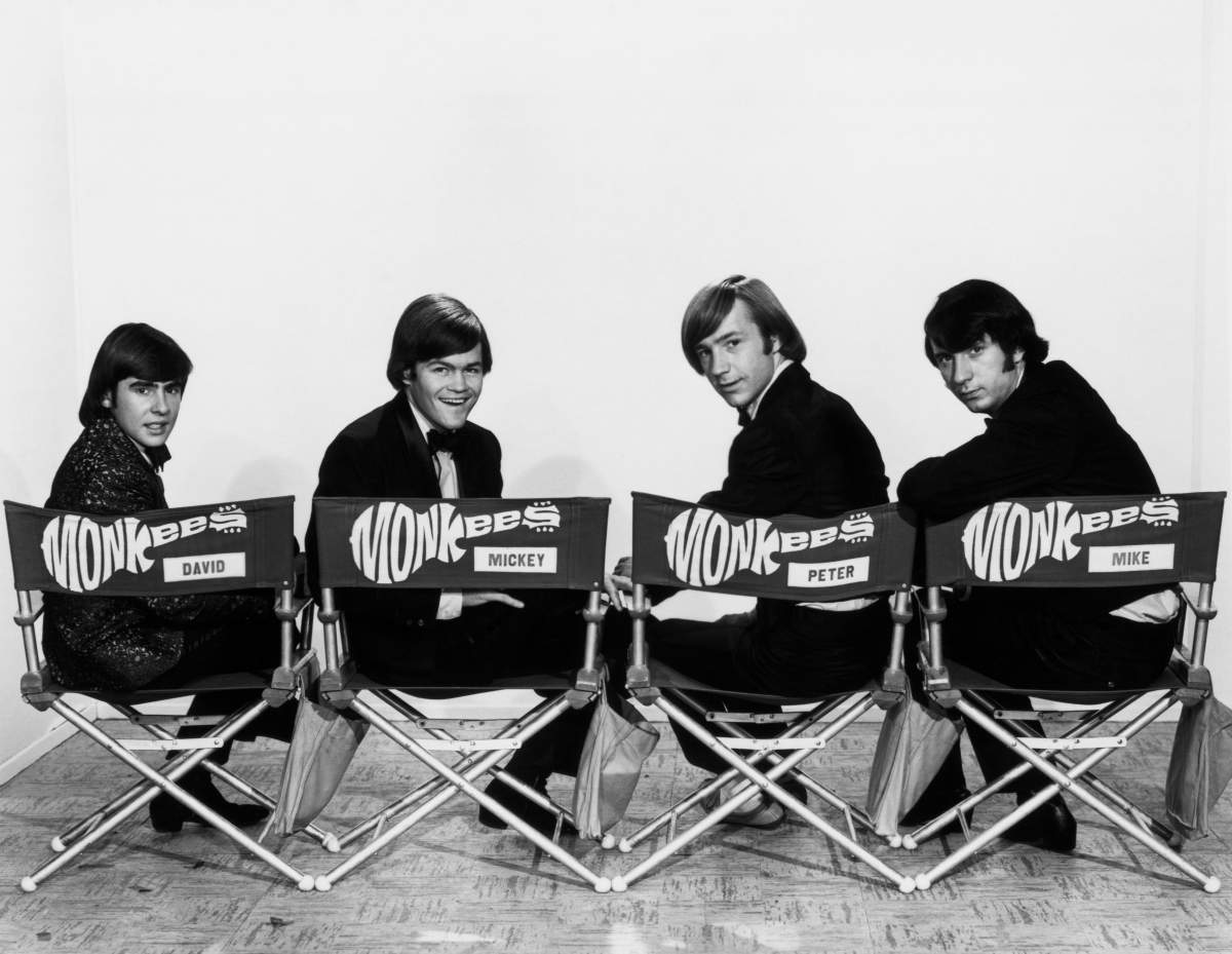 In four director chairs are seated members of The Monkees. (L-R) David Jones, Mickey Dolenz, Peter Tork and Michael Nesmith.