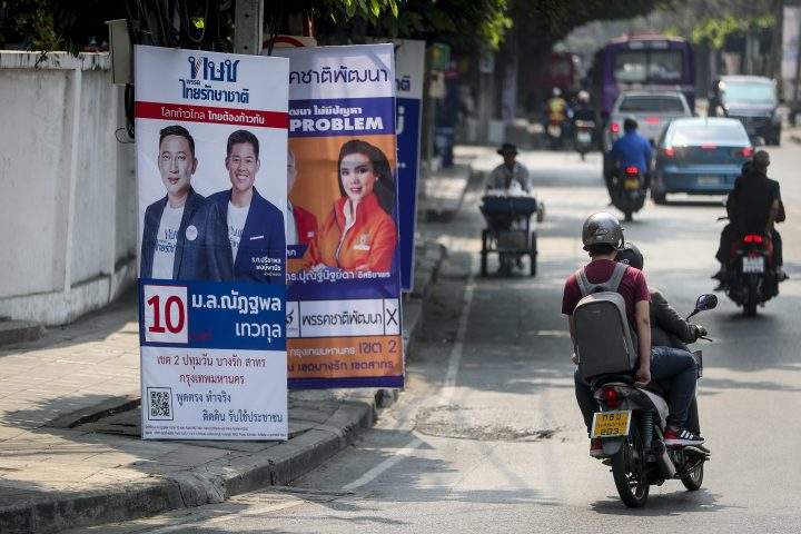 People drive past an electoral poster with the portrait of Thai Raksa Chart Party’s leader Preechapol Pongpanich, second-left, and its party’s Member of Parliament constituency candidate, left, in Bangkok, Thailand, 13 February 2019.