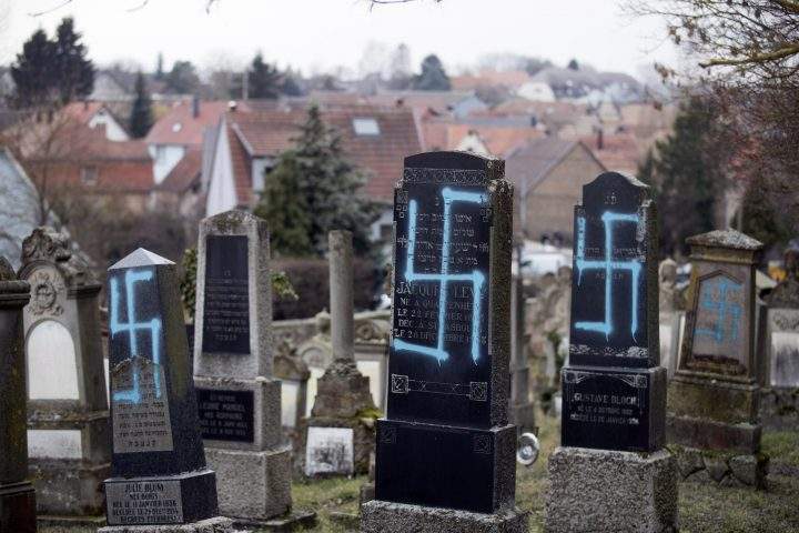 Vandalized tombs with tagged swastikas are pictured in the Jewish cemetery of Quatzenheim, eastern France, Tuesday, Feb.19, 2019.