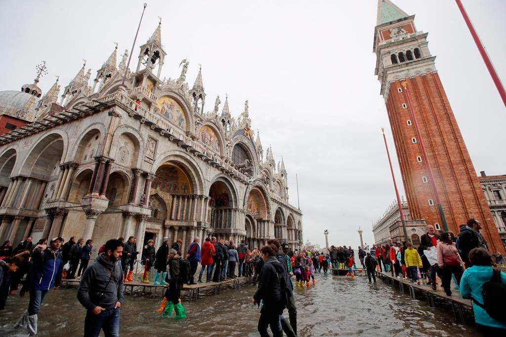 In this Nov. 1, 2018 file photo, tourists walk in flooded St. Mark’s Square in Venice, Italy.
