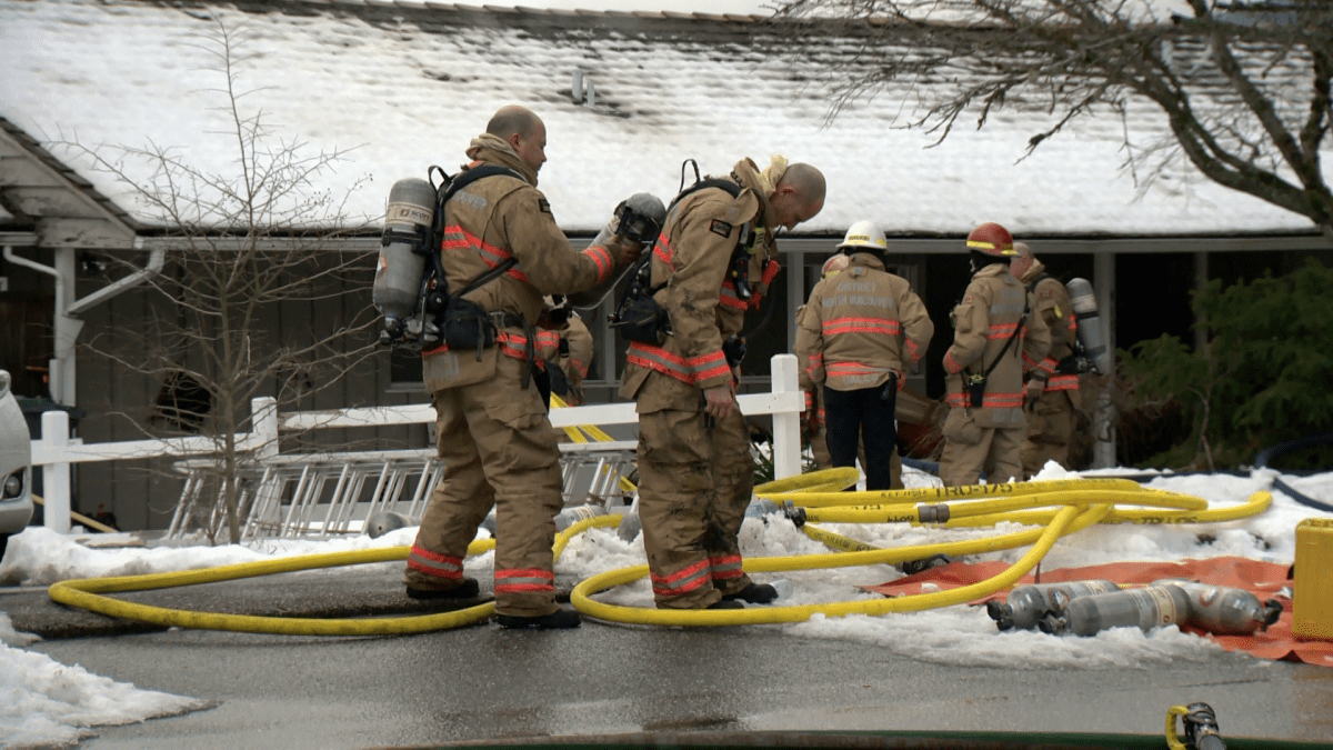 Firefighters clean up after extinguishing a fire in North Vancouver on Saturday. 
