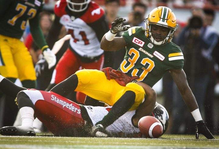 Edmonton Eskimos’ Shakir Bell, top, is hauled down by Calgary Stampeders’ Mylan Hicks during first half CFL preseason football action in Calgary, Saturday, June 11, 2016.
