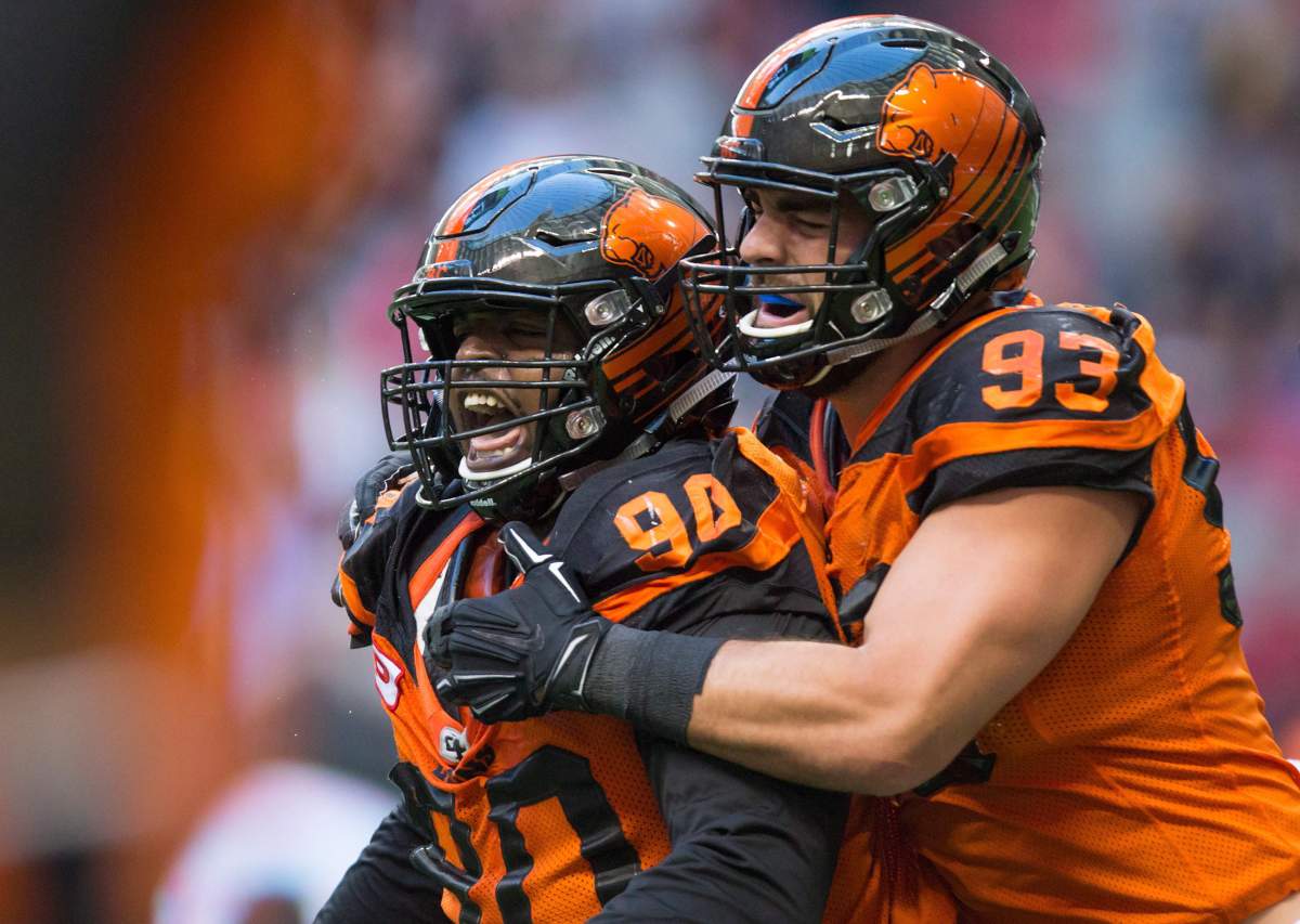 B.C. Lions' Mic'hael Brooks, left, and Craig Roh celebrate after Brooks stopped Calgary Stampeders' quarterback Drew Tate on a third and goal play during the first half of a CFL football game in Vancouver, B.C., on Saturday June 25, 2016. 