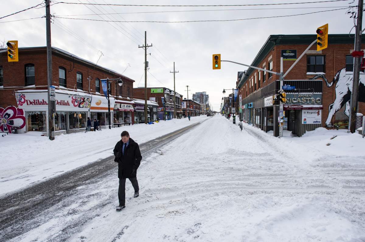 A pedestrian uses the roadway to make his way up Bank Street in Ottawa's Glebe neighbourhood during a winter storm on Wednesday, Feb. 13, 2019.