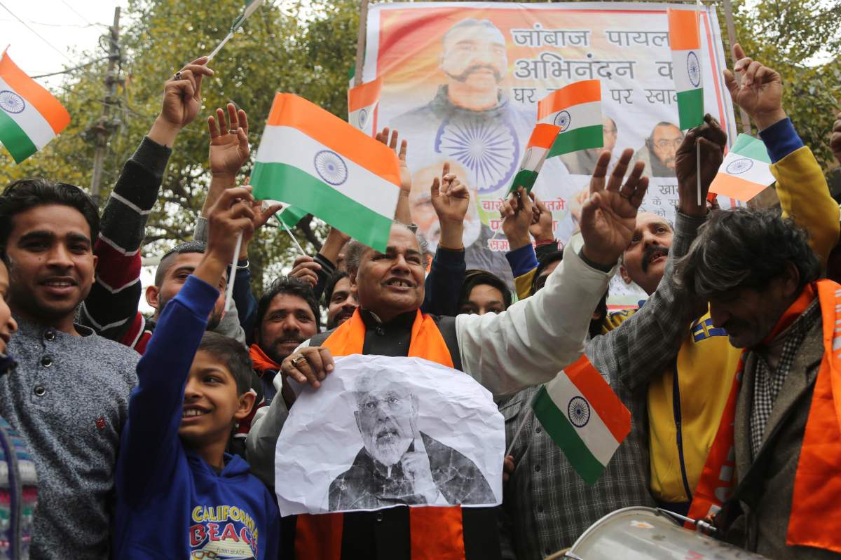 Indians wave national flags as they wait for the release of an Indian air force pilot by Pakistani authorities, in Jammu, India, Friday, March 1, 2019.