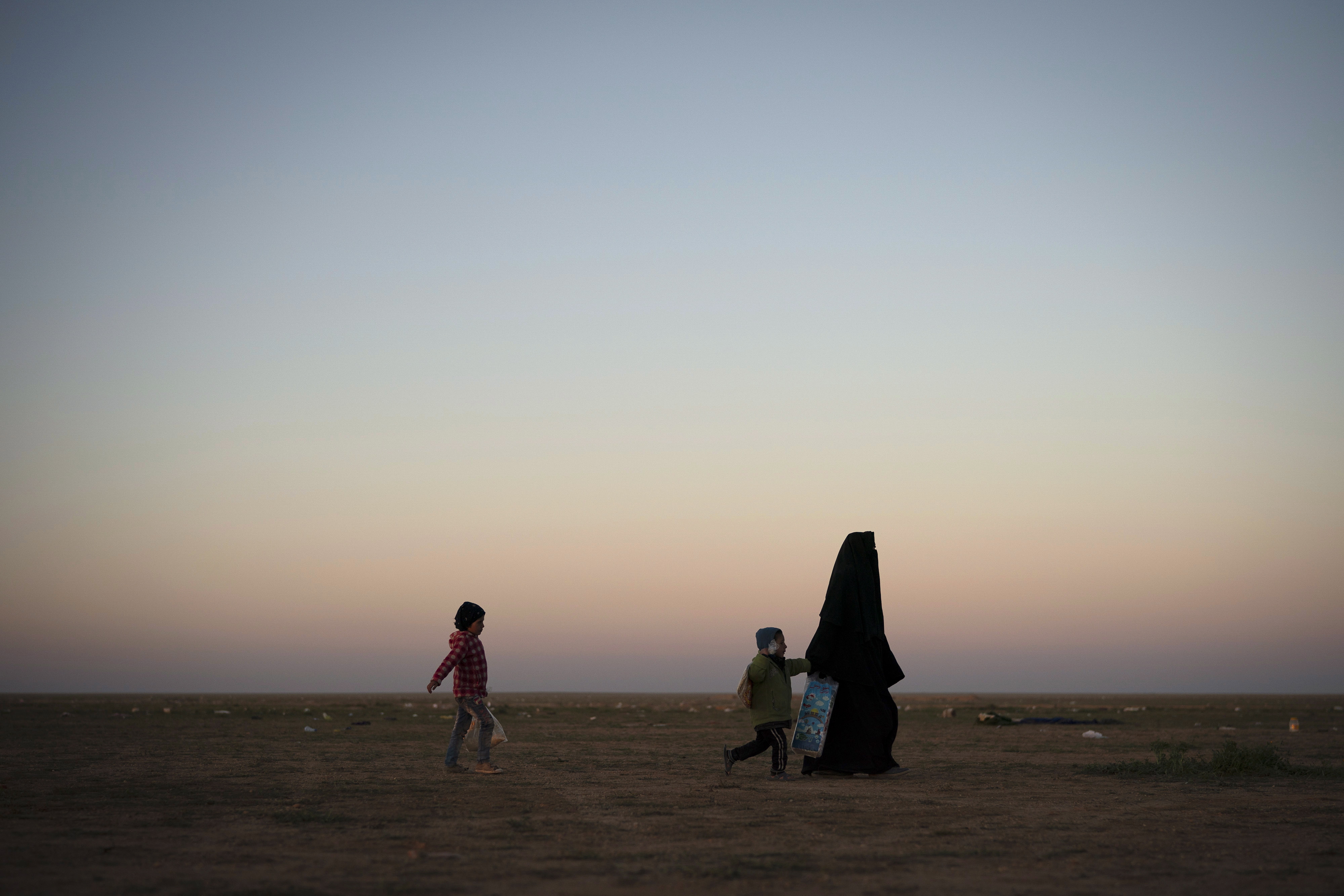 A woman walks with children at Syrian Democratic Forces (SDF) screening area after being evacuated out of last territory held by ISIS, Baghouz, Syria, March 1, 2019.