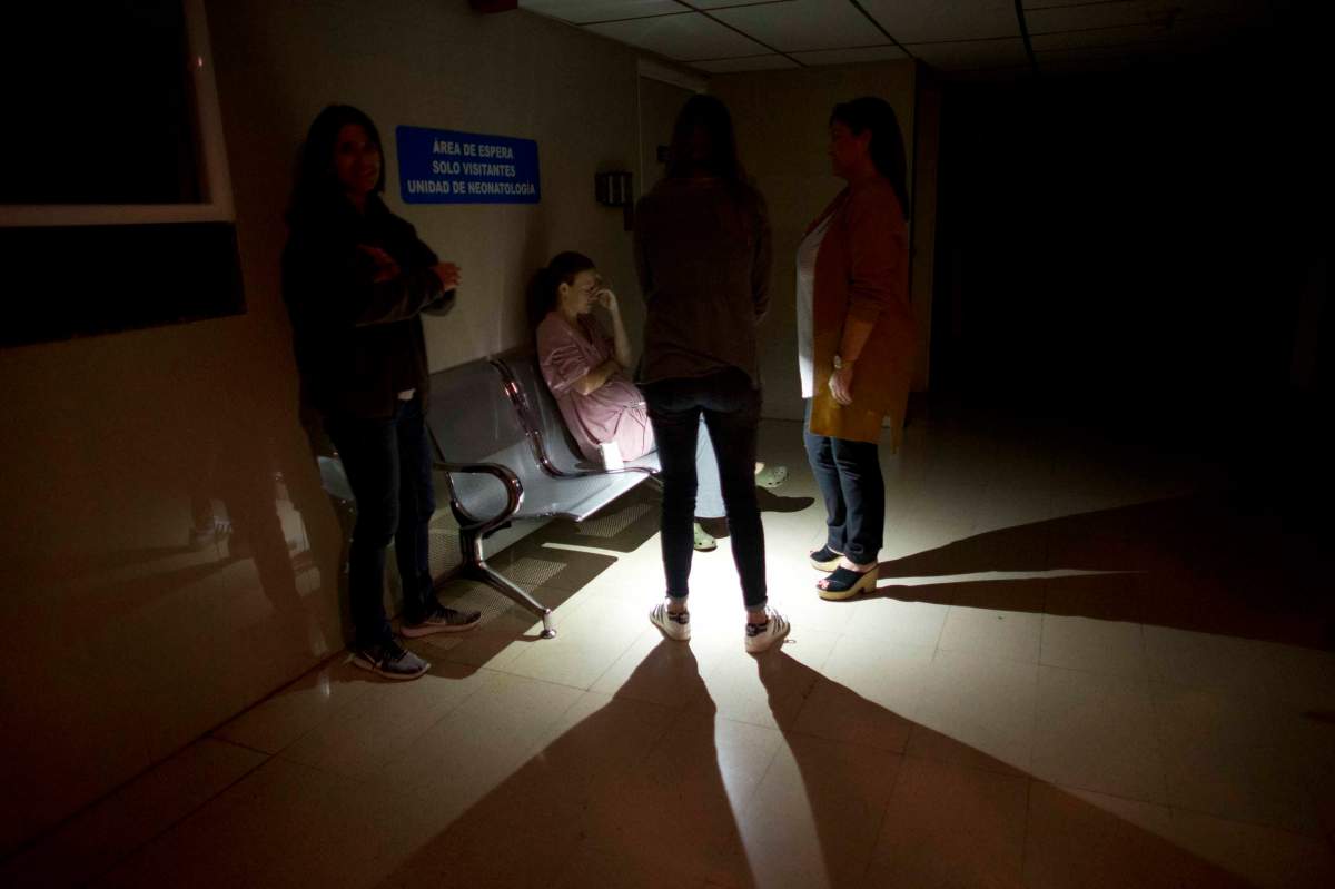 Mothers and relatives wait outside of an intense care room for babies at a clinic, during a power outage in Caracas, Venezuela, Thursday, March 7, 2019. A power outage left much of Venezuela in the dark early Thursday evening in what appeared to be one of the largest blackouts yet in a country where power failures have become increasingly common. (AP Photo/Ariana Cubillos)