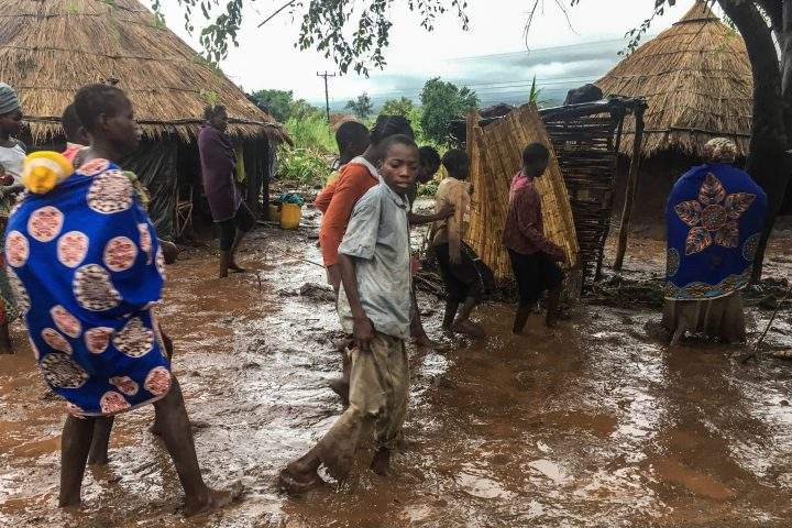 Inhabitants of Chiluvi, a village in central Mozambique, walk along a flooded and muddy street after Cyclone Idai.