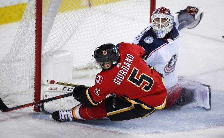 Columbus Blue Jackets goalie Sergei Bobrovsky, right, blocks the net on Calgary Flames’ Mark Giordano during first period NHL hockey action in Calgary, Tuesday, March 19, 2019.