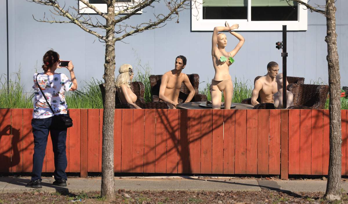 In this photo taken Monday, March 18, 2019, a woman stops to photograph a display of mannequins in Santa Rosa, Calif.