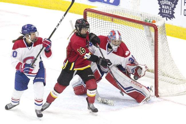 Calgary Inferno's Rebecca Leslie (centre) tries to tip the puck past Les Canadiennes de Montreal's goaltender Emerance Maschmeyer during second period action in the 2019 Clarkson Cup game in Toronto, March 24, 2019. 