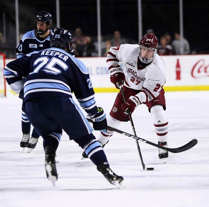 Massachusetts' Jake McLaughlin skates with the puck in front of Maine's Brady Keeper during the first period of a college hockey game on Saturday, March 2, 2019, in Amherst, Mass.
