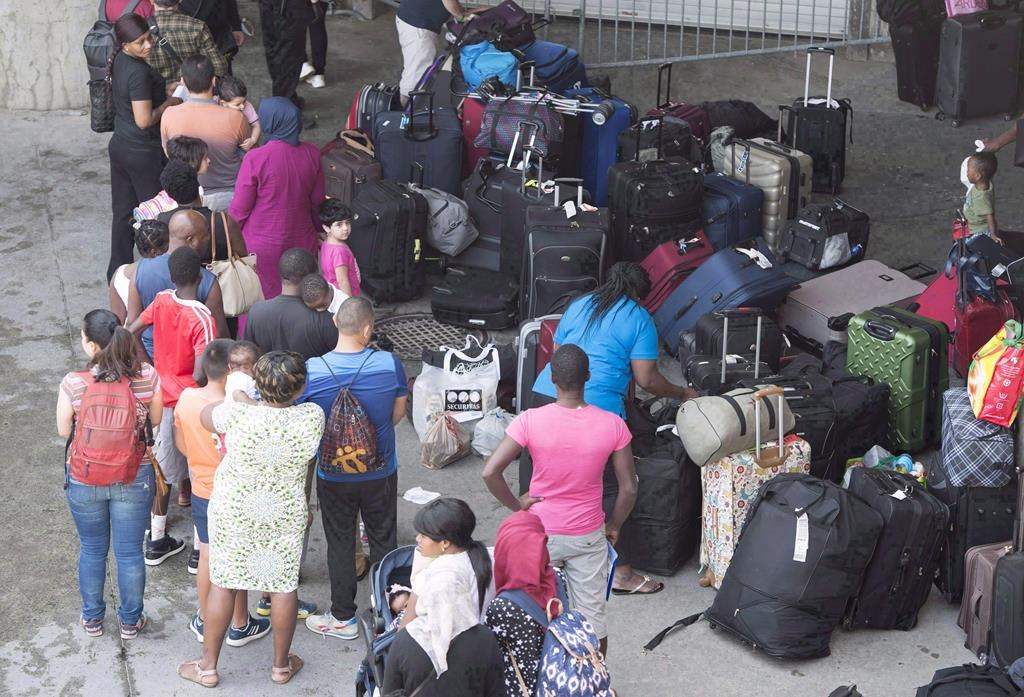 Asylum seekers line up to enter Olympic Stadium Friday, Aug. 4, 2017 near Montreal. THE CANADIAN PRESS/Paul Chiasson