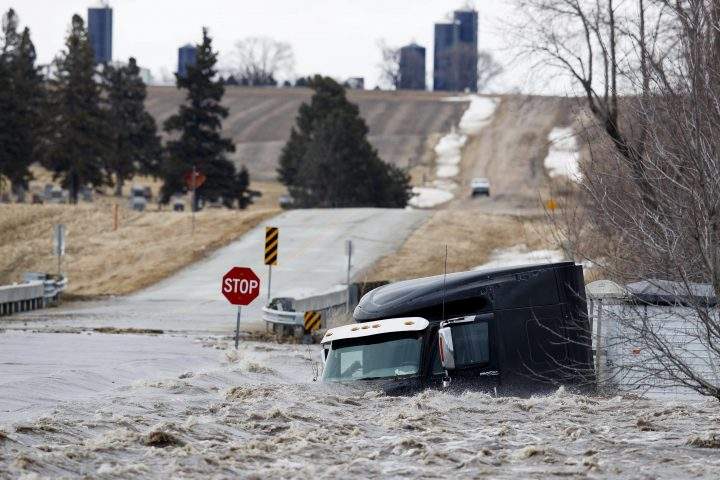 A semi truck and trailer are swept off the road by floodwaters Thursday, March 13, 2019, in Arlington, Neb.