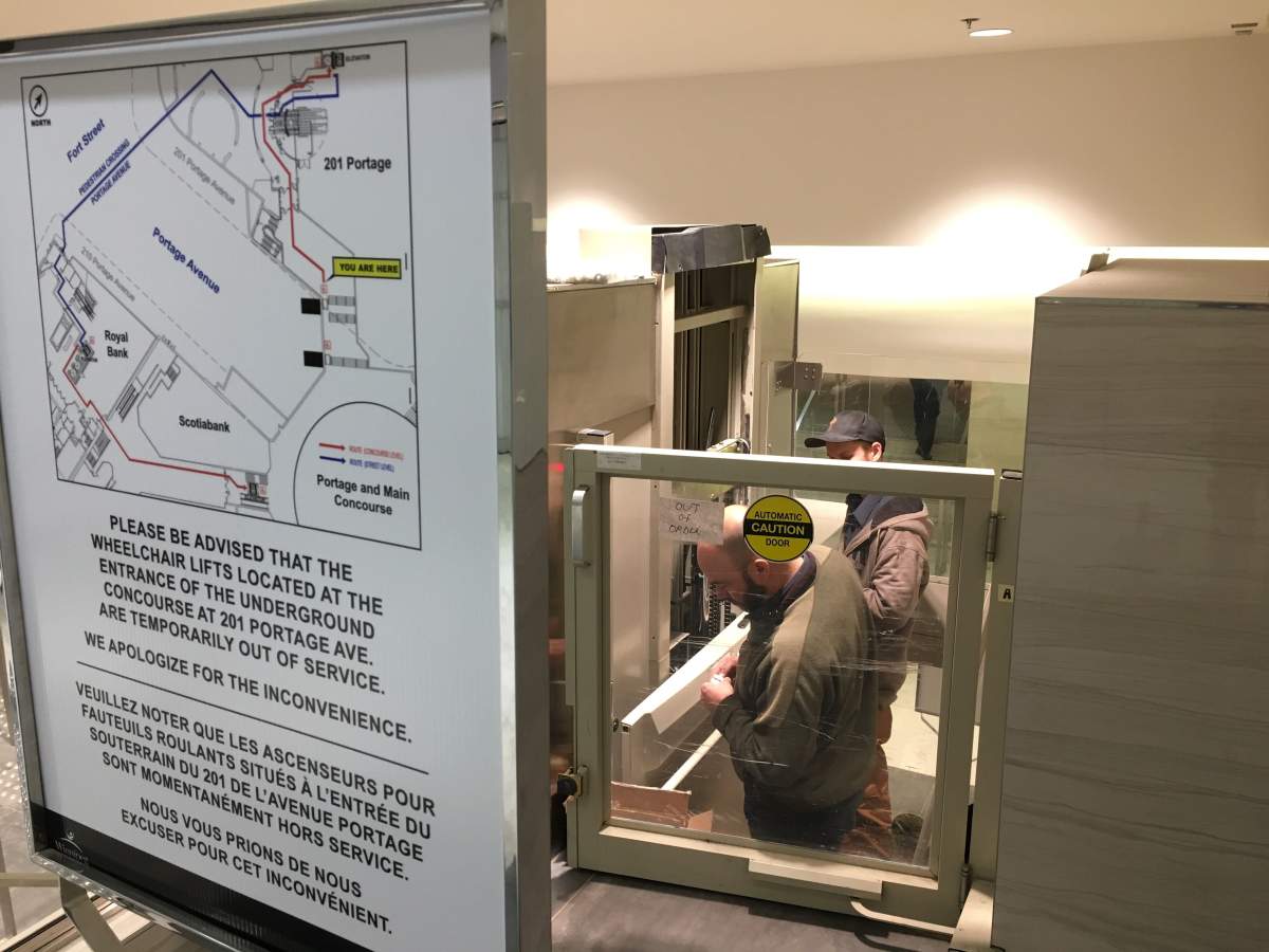 Technicians work on the broken wheelchair lift in the underground corridor at 201 Portage Avenue.