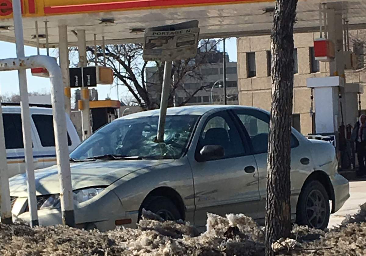 A bus stop sign rests in a car after being impaled through a front windshield.