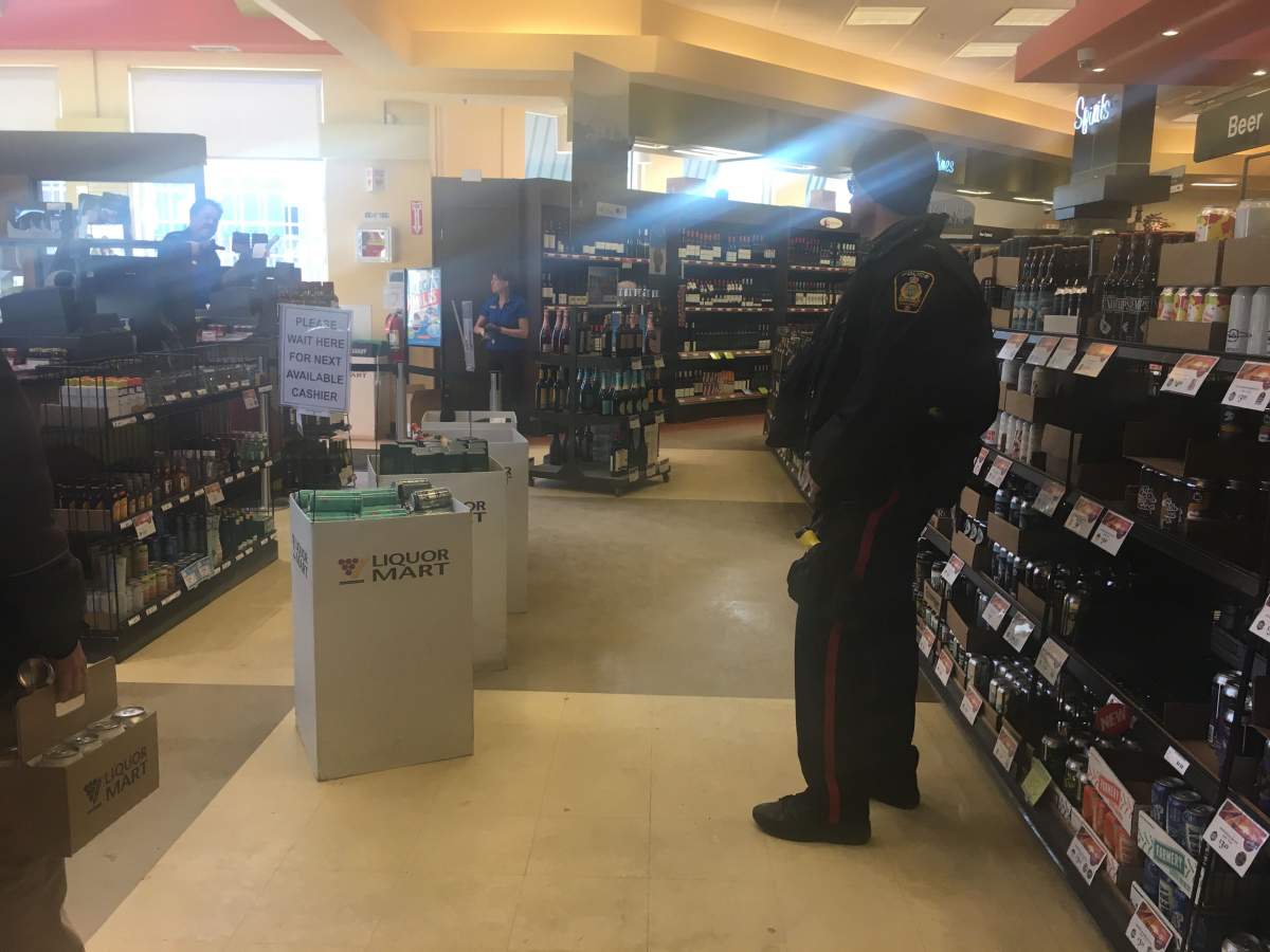 A fully uniformed police officer roams the Osborne Village Liquor Mart Friday, March 22, 2019.