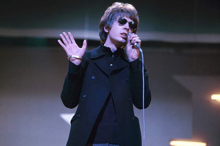 Scott Walker of the Walker Brothers performing on stage wearing sunglasses.