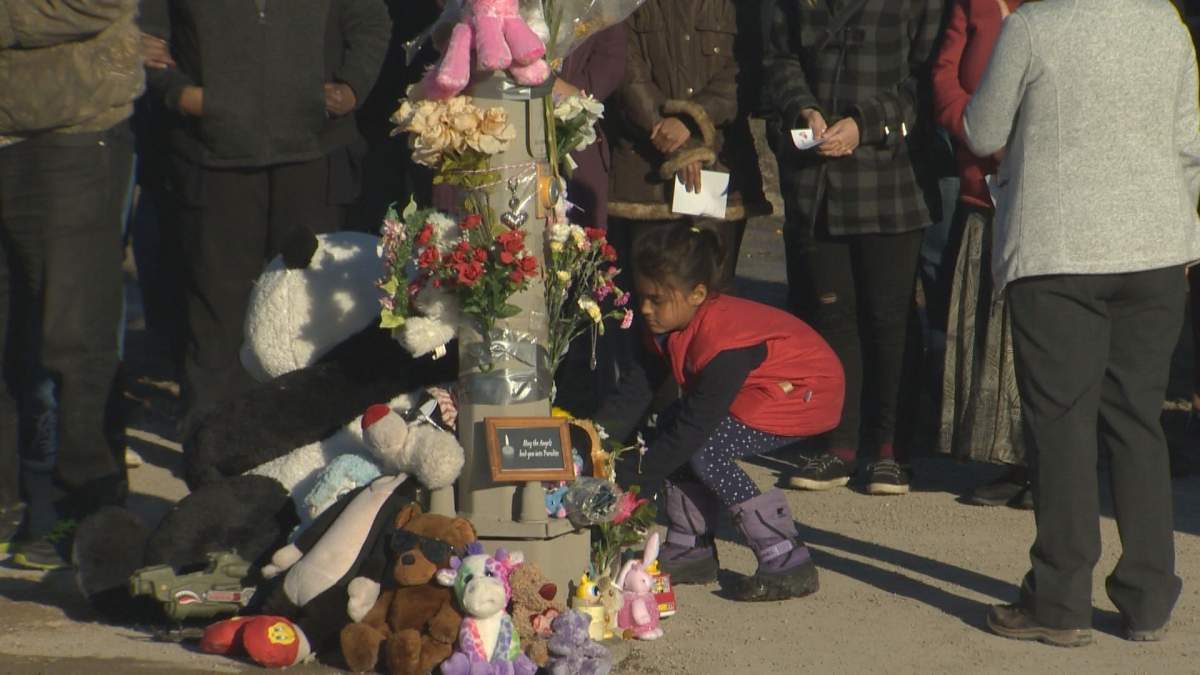 A young girl places flowers at a tribute