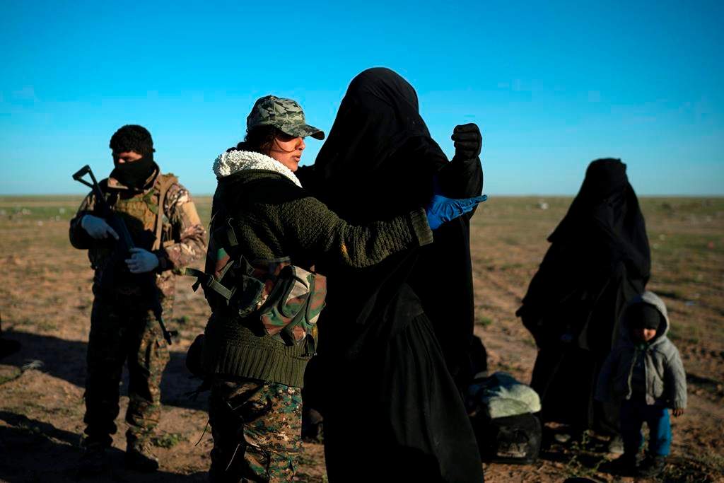 U.S.-backed Syrian Democratic Forces fighter frisks woman fleeing during the collapse of ISIS, Baghouz, Syria, on March 1, 2019. (AP Photo/Felipe Dana).