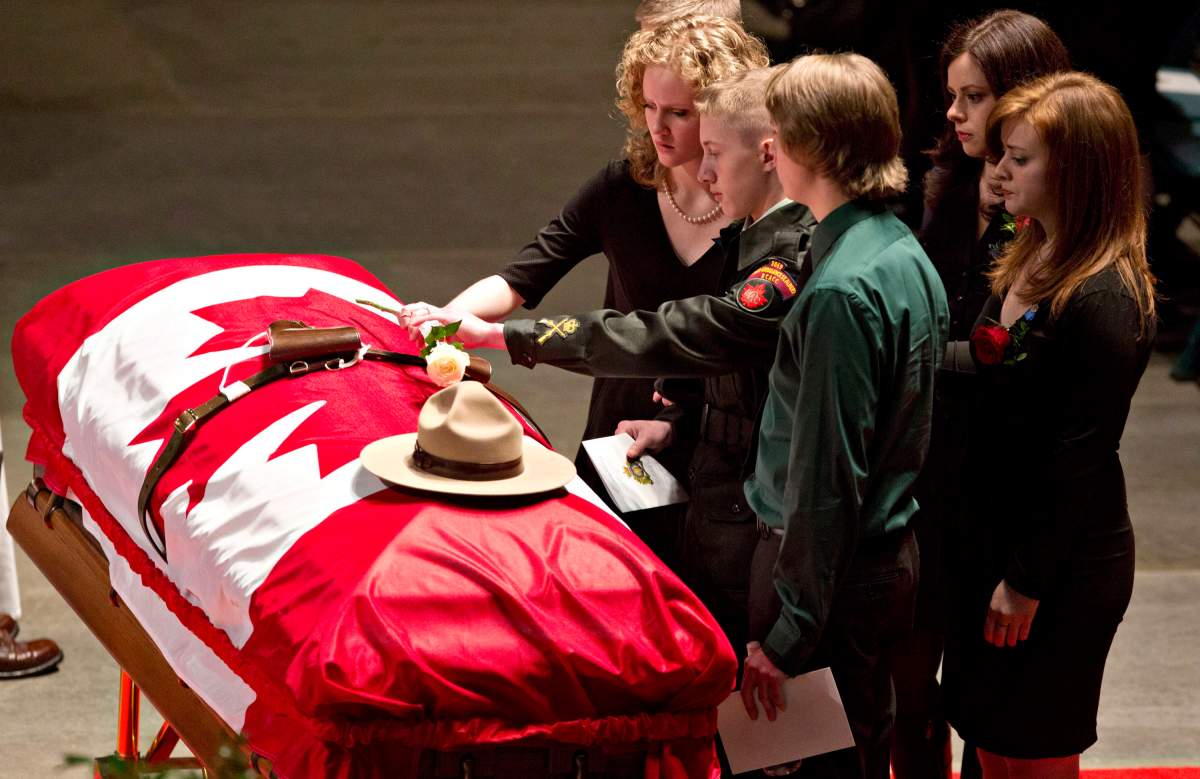 Matthew Wynn, son of slain RCMP Constable David Wynn places a flower on his dads casket during the funeral for Constable Wynn, in St. Albert, Alta., on Monday, January 26, 2015.