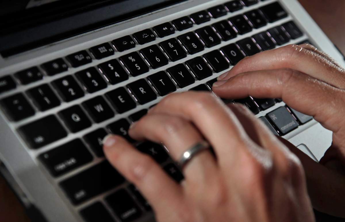 FILE- In this June 19, 2017, file photo, a person types on a laptop keyboard in North Andover, Mass. (AP Photo/Elise Amendola, File).