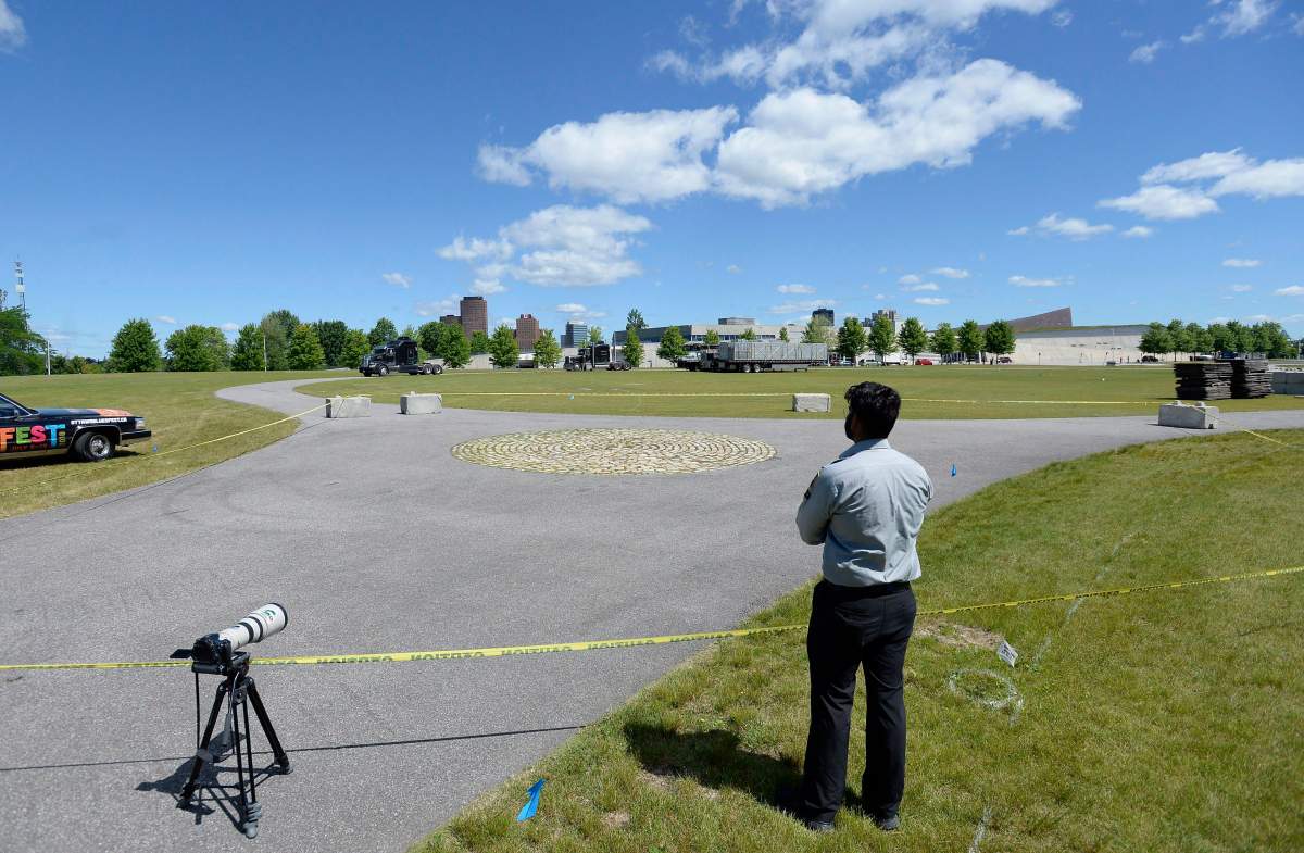 A security guard stands in front of caution tape keeping people from disturbing a killdeer bird that laid a nest and eggs on a cobblestone path on the site of the Ottawa Bluesfest music festival, next to the Canadian War Museum in Ottawa on Monday, June 25, 2018.
