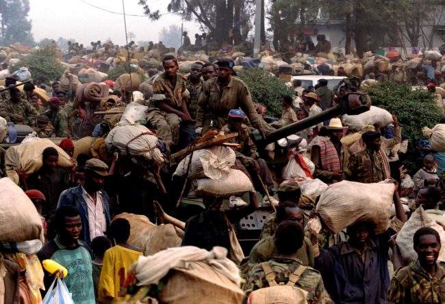 Rwandan government soldiers atop a tank equipped with a 90mm gun flee civilians in front of advancing RPF forces with civilians, July 17, 1994.
