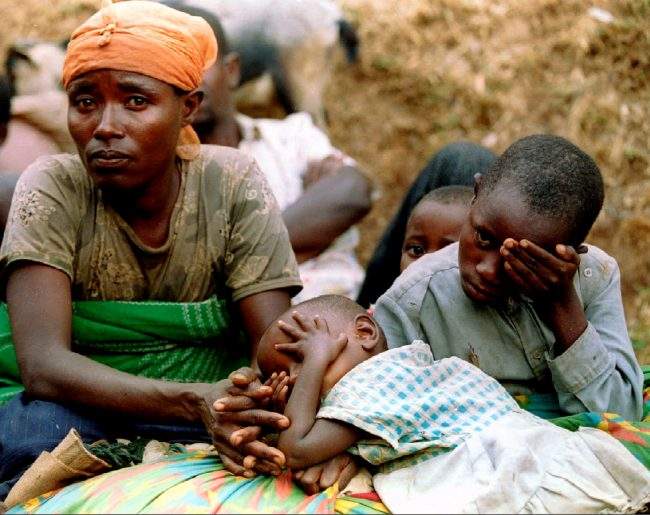 A Hutu woman and her children take a rest as they flee on the edge of the French security zone for the Zairean border August 16, 1994.