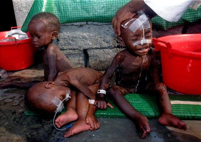 Three Rwandan orphans in medical treatment, waiting to be washed by relief worker at Ndoshu orphanage, Aug. 16, 1994.