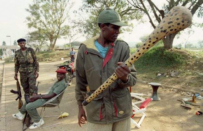 A Rwandan Patriotic Front rebel observes a nail-spiked club found near a militia checkpoint which was abandoned after the rebel victory in Kigali, Rwanda July 7, 1994.