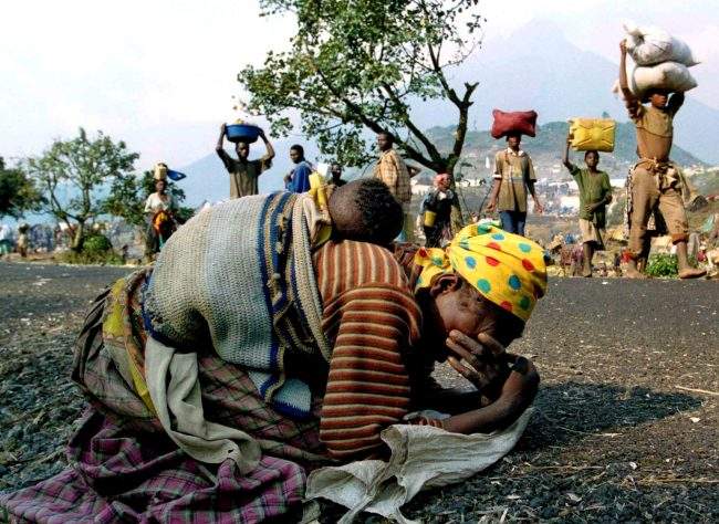 A Rwandan woman collapses with her baby on her back alongside the road connecting Kibumba refugee camp and Goma, July 28, 1994.