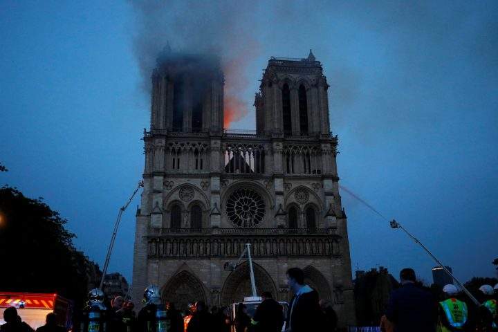 Paris Fire brigade members spray water onto the facade of the Notre Dame Cathedral.