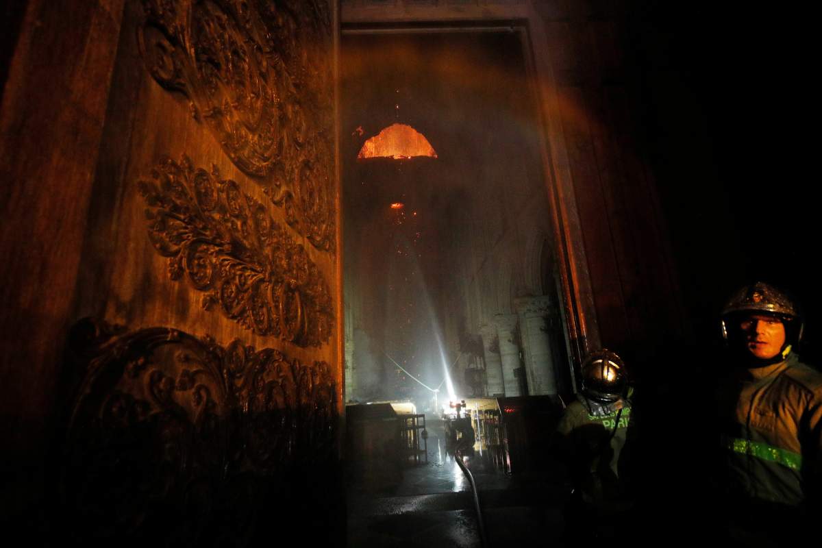 Paris Fire Brigade members are seen at an entrance that looks into the Notre Dame Cathedral as a fire continues to burn in Paris, France, April 15, 2019.
