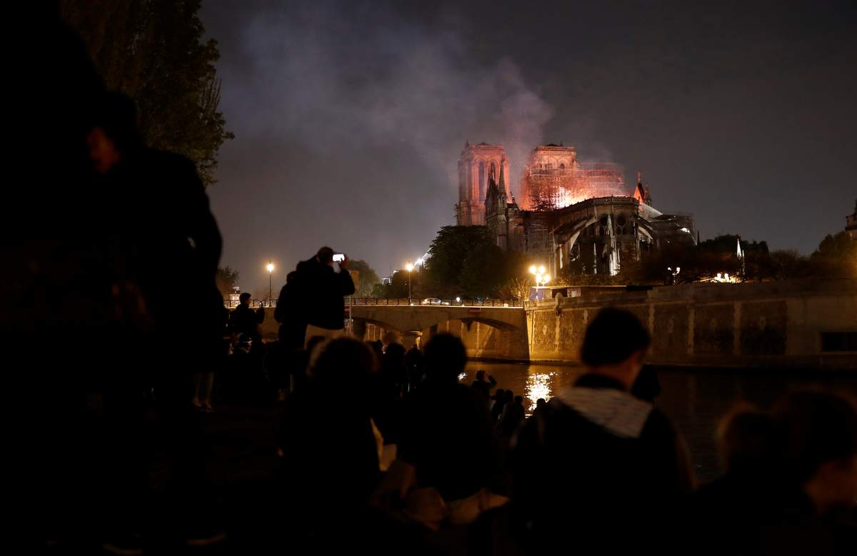 People watch as firefighters douse flames of the burning Notre Dame Cathedral in Paris, France April 15, 2019.
