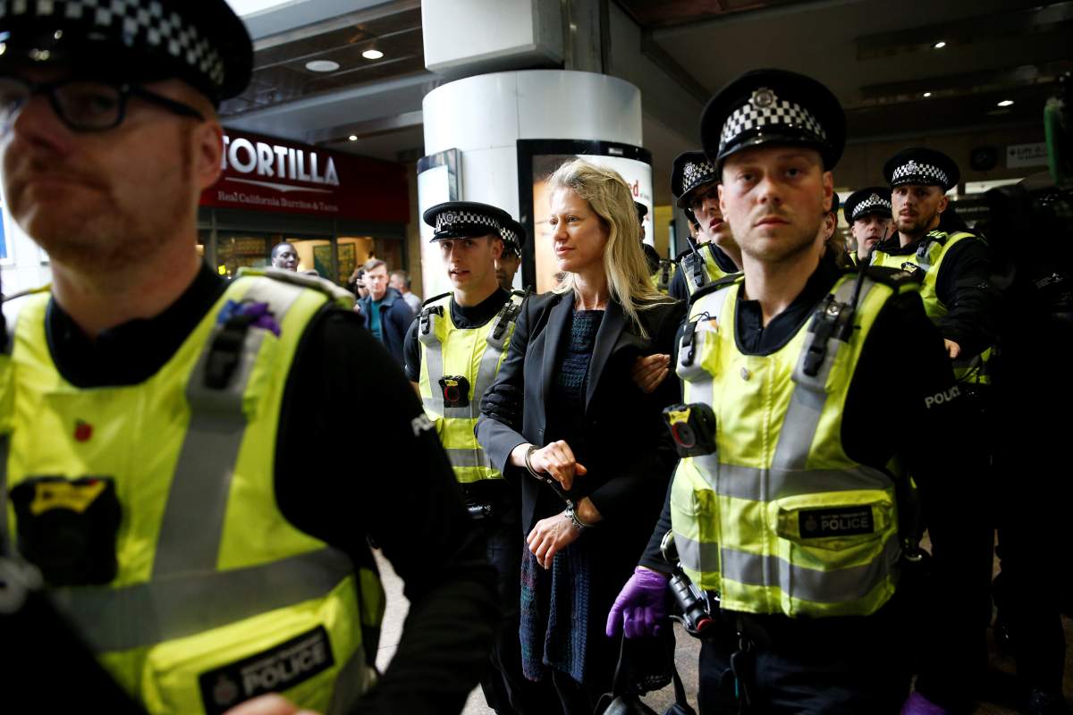 Police detain a climate change activist demonstrating during the Extinction Rebellion protest at Canary Wharf DLR station in London on April 17, 2019.
