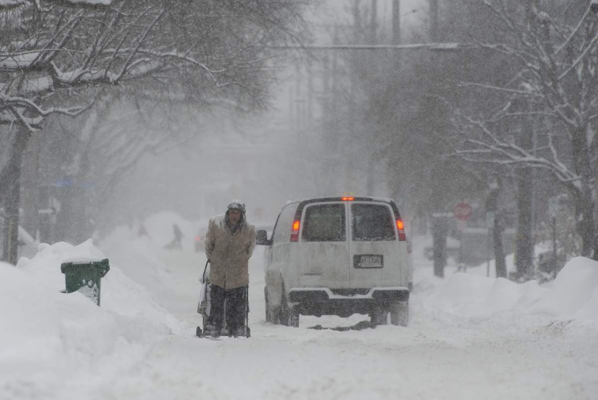 A vehicle slows as it passes a man pulling a shopping cart along the road in Ottawa on Wednesday, January 23, 2019.
