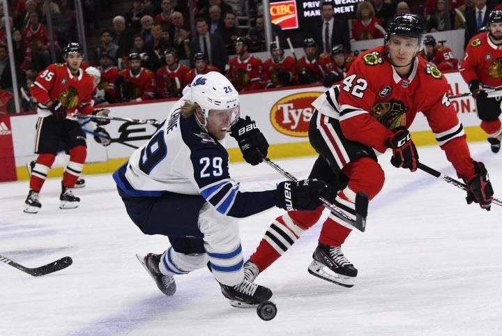 Winnipeg Jets right wing Patrik Laine (29) and Chicago Blackhawks defenseman Gustav Forsling (42) fight for the puck during the first period of an NHL hockey game Monday, April 1, 2019, in Chicago.