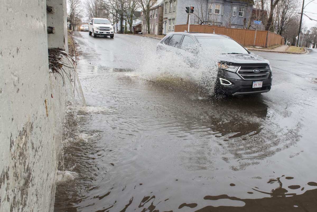 Flood water from the St. John River pours over a retaining wall flooding a low lying street in Fredericton on Sunday, April 21, 2019.