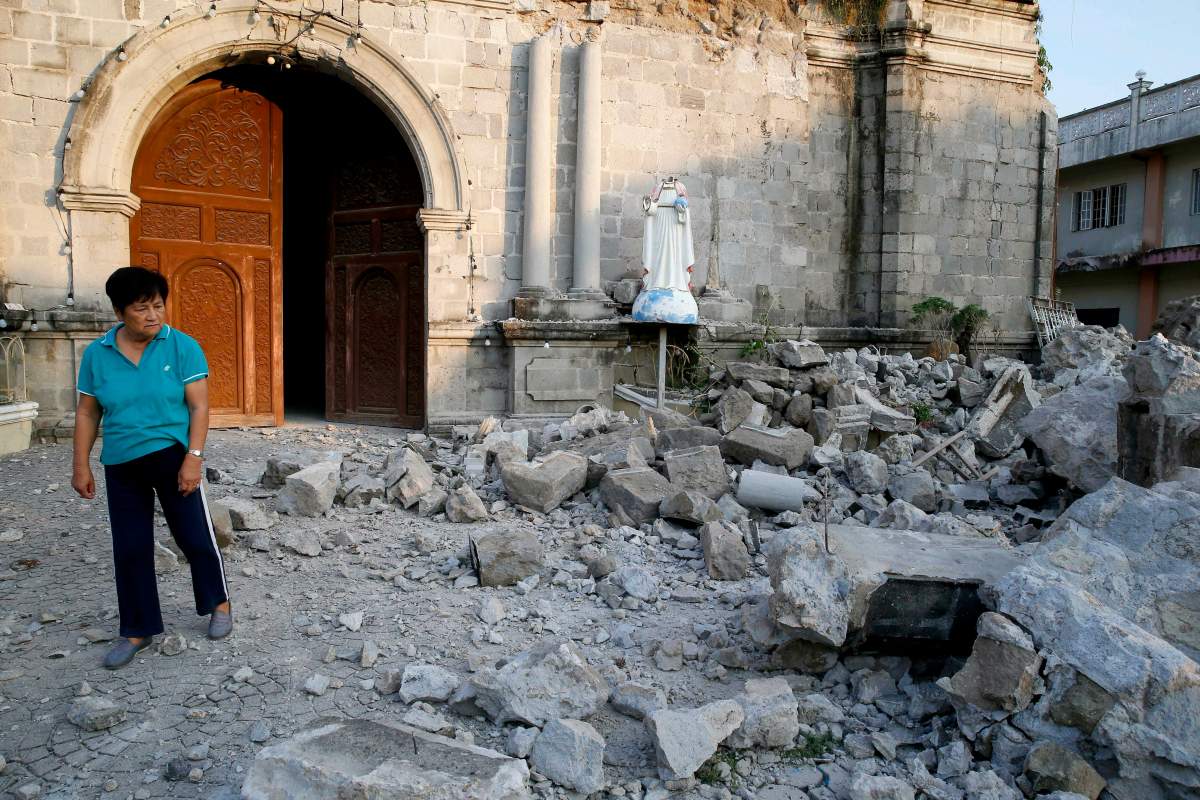 A resident looks at the rubble of St. Catherine church, including a toppled head of a statue, following a 6.1 magnitude earthquake in Porac township, Pampanga province, north of Manila, Philippines, Tuesday, April 23, 2019.