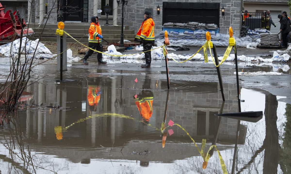 Workers build a dike with sandbags around a house in a flooded neighbourhood in Ile Bizard, Que., on Wednesday, April 24, 2019.