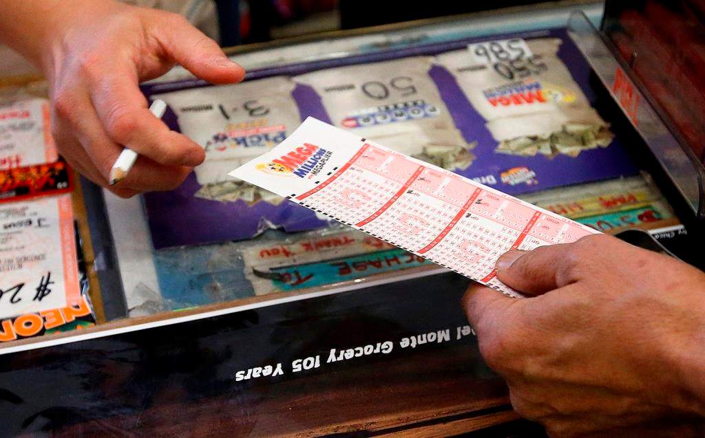 FILE - In this Tuesday, Dec. 17, 2013 file photo, Keith Ganatra, right, owner of the Del Monte Market, takes the numbers form picked by a customer, as he sells Mega Millions lottery tickets at a brisk pace in Laveen, Ariz.