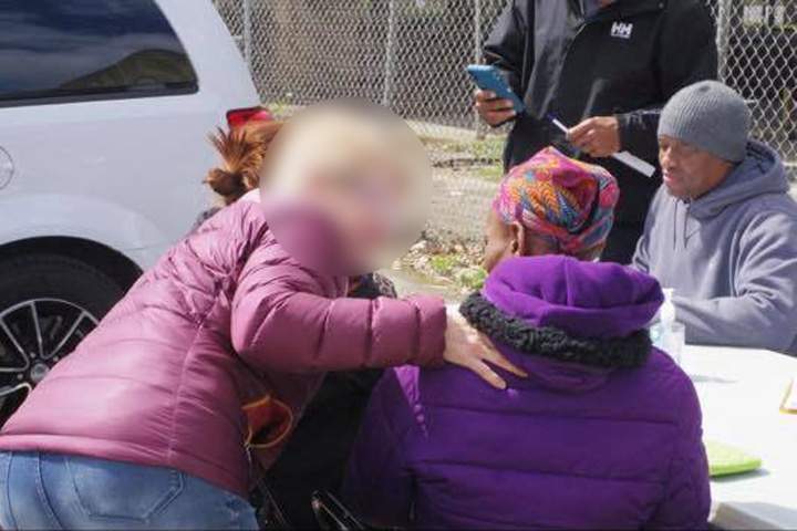 An individual claiming to offer cancer screening, right, conducts test alongside a van in Louisville, Ky., in late March 2019.