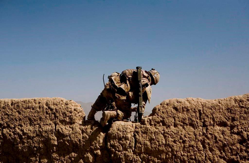 A Canadian soldier with 1st RCR Battle Group, The Royal Canadian Regiment, climbs over a wall as he patrols with his unit to find improvised explosive devices, or IEDs in the Panjwayi district, southwest of Kandahar, Afghanistan on June 6, 2010.