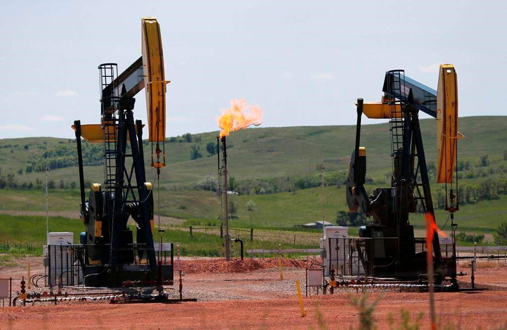 FILE -In this June 12, 2014 file photo, oil pumps and natural gas burn off in Watford City, N.D.